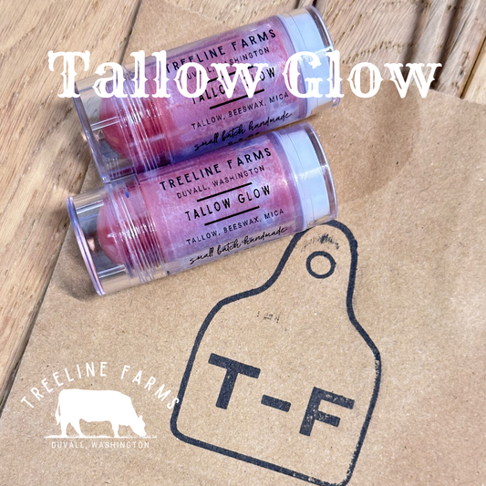 Two tubes of Treeline Farms’ tallow glow on a background of a branded paper and wood.